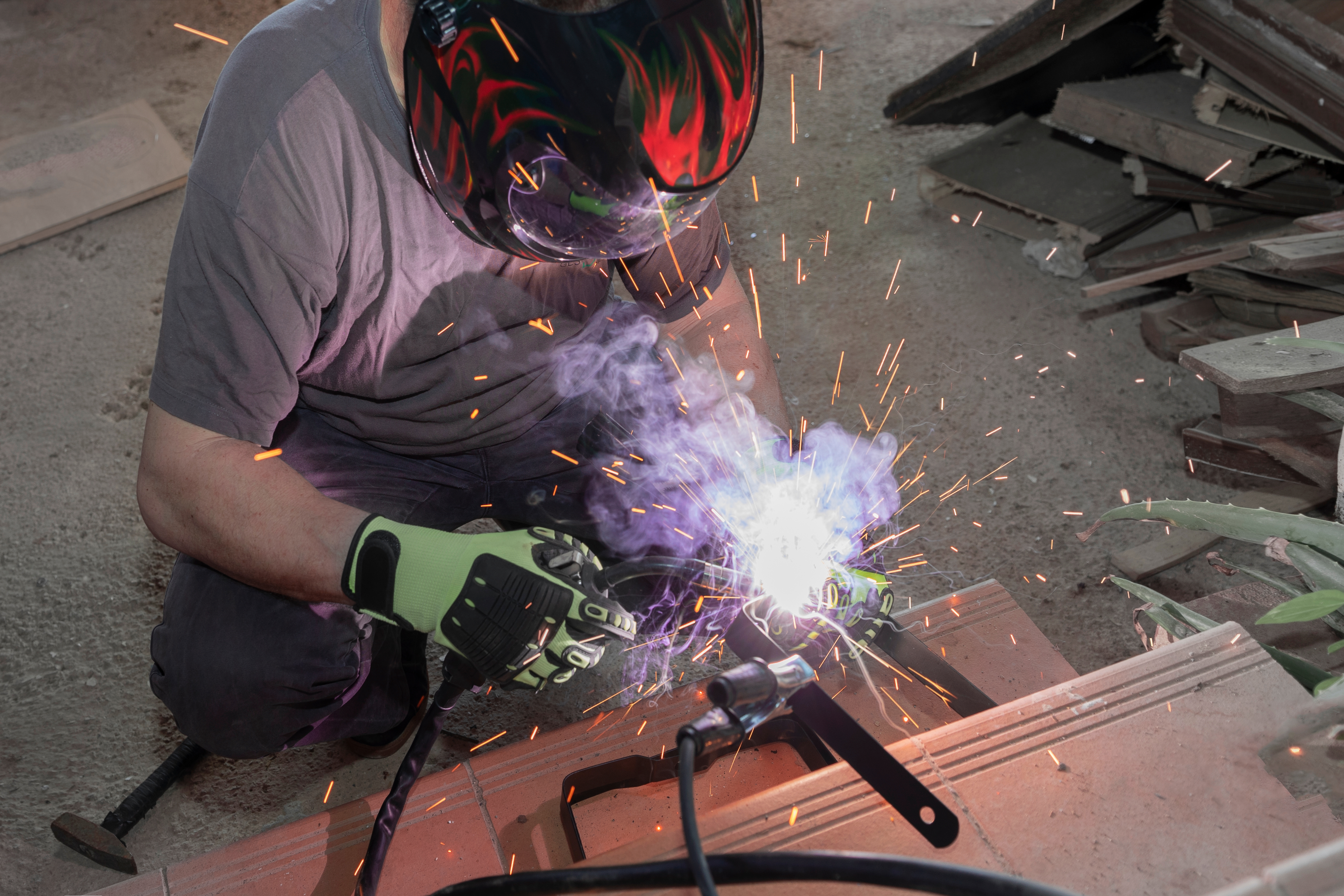 a man in a protective mask mask works with a welding tool for metal